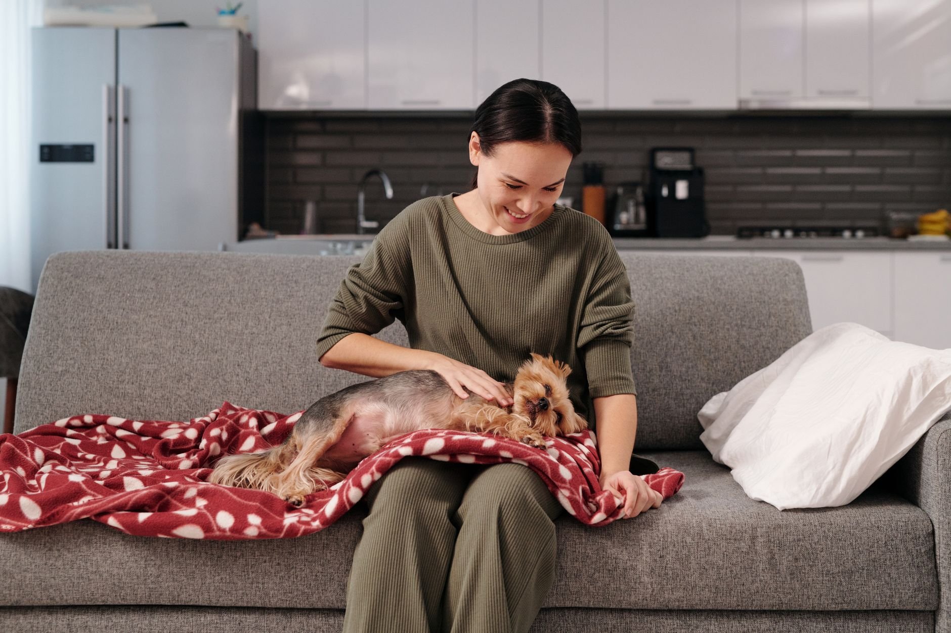 Woman petting a small dog on a cozy couch at home